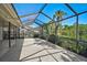 A wide view of a screened-in patio and lake surrounded by palm trees and lush greenery at 6017 Marella Dr, Sarasota, FL 34243