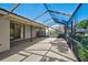 Screened-in back patio with tile and textured concrete flooring, with a partial view of plants at 6017 Marella Dr, Sarasota, FL 34243
