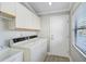 Functional laundry room with sink, washer, dryer, storage cabinets and an exterior door at 6017 Marella Dr, Sarasota, FL 34243