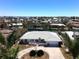 An aerial view of a well-maintained home featuring a white tile roof, circular driveway, and tropical landscaping in a waterfront community at 618 Gladstone Ln, Holmes Beach, FL 34217