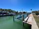 Boat dock with a boat lift on a scenic canal surrounded by palms at 618 Gladstone Ln, Holmes Beach, FL 34217