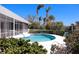 A blue in-ground pool surrounded by lush landscaping in a screened-in enclosure at 618 Gladstone Ln, Holmes Beach, FL 34217