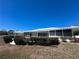 Rear view of property with a screened in porch and manicured landscaping at 618 Gladstone Ln, Holmes Beach, FL 34217