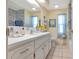Bright bathroom with a large mirror, white cabinets, and yellow walls accented with blue curtains and a framed lighthouse print at 633 Cervina S Dr, Venice, FL 34285