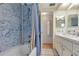 Bathroom features a shower-tub with blue marble-style walls, a vanity with a sink, and access to other rooms at 633 Cervina S Dr, Venice, FL 34285