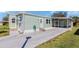 Home featuring light green siding, a spacious driveway, and an inviting, screened-in lanai for outdoor relaxation at 633 Cervina S Dr, Venice, FL 34285