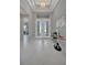 Bright foyer with white tiled floors, tray ceiling, chandelier, and double doors at 6620 35Th E Ct, Sarasota, FL 34243
