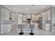 A bright kitchen with white cabinets, marble countertops, stainless steel appliances, and an island with seating at 6620 35Th E Ct, Sarasota, FL 34243