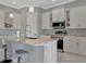 White kitchen features marble countertops, an island with bar seating, and stainless steel appliances at 6620 35Th E Ct, Sarasota, FL 34243