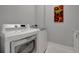 Modern laundry room with white washer and dryer, and light gray walls at 6620 35Th E Ct, Sarasota, FL 34243