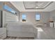 Spacious main bedroom featuring a large bed, tray ceiling, and ample natural light from multiple windows at 6620 35Th E Ct, Sarasota, FL 34243