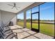Covered lanai with a ceiling fan, chairs and views of the yard and pond at 6620 35Th E Ct, Sarasota, FL 34243