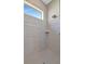 Modern walk-in shower with gray tiling, sleek fixtures, and a window for natural light at 6620 35Th E Ct, Sarasota, FL 34243