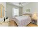 Bright bedroom with a ceiling fan, light wood floors, large window, and a queen-sized bed with floral bedding at 7102 42Nd E Ct, Sarasota, FL 34243