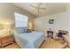 Inviting bedroom featuring a window with blinds, light colored walls, wood floors and ceiling fan plus a queen size bed at 7102 42Nd E Ct, Sarasota, FL 34243