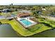A pristine pool area is surrounded by trees, green grass, and a nearby pond at 7102 42Nd E Ct, Sarasota, FL 34243