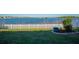Scenic backyard view features a white picket fence and lush landscaping that overlooks a beautiful serene lake at 718 Tanana Fall Dr, Ruskin, FL 33570
