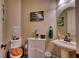 Cozy half bath with decorative picture, round mirror, toilet, and white pedestal sink at 9902 Craftsman Park Way, Palmetto, FL 34221