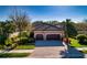 Charming home featuring a well-manicured lawn, mature landscaping, and a three-car garage with a tile roof at 9902 Craftsman Park Way, Palmetto, FL 34221
