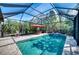 Beautiful screened-in pool with patio furniture, an umbrella, and lush landscaping, perfect for outdoor relaxation at 9902 Craftsman Park Way, Palmetto, FL 34221