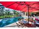 A screened-in pool area with a table under a red umbrella and lush landscaping at 9902 Craftsman Park Way, Palmetto, FL 34221