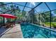 Screened pool with a red patio umbrella and plenty of space for outdoor dining and entertaining at 9902 Craftsman Park Way, Palmetto, FL 34221