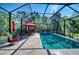 Stunning pool area featuring a screened-in enclosure, stone pavers, lush landscaping, and a sitting area at 9902 Craftsman Park Way, Palmetto, FL 34221