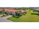 Aerial view of a home with a red tile roof, manicured lawn, and a view of a pond at 10008 Carnoustie Pl, Bradenton, FL 34211