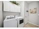 This laundry room features white cabinets above a washer and dryer set for ample storage at 10008 Carnoustie Pl, Bradenton, FL 34211