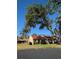 Serene view of a home with a red tile roof, complemented by mature trees and a well-manicured lawn at 1216 58Th W St, Bradenton, FL 34209