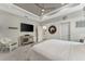 Bedroom with tray ceilings, ceiling fan, TV and decorative wall art, plus view of the ensuite bathroom at 16966 Rosedown Gln, Parrish, FL 34219