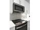 Modern kitchen featuring stainless steel microwave over a glass cooktop and grey mosaic backsplash at 16966 Rosedown Gln, Parrish, FL 34219