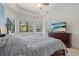 Tranquil bedroom featuring tray ceilings, three windows with natural light, and a dresser with television at 17045 Polo Trl, Bradenton, FL 34211