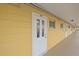 Exterior hallway featuring unit entrance with white door, painted yellow walls, and overhead lighting at 2155 Wood St # A20, Sarasota, FL 34237