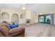 Expansive living room features carpeted floors, a ceiling fan, and access to an outdoor pool at 25422 Aysen Dr, Punta Gorda, FL 33983