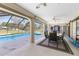 Enjoy dining poolside on this partially covered patio featuring roll down privacy screens and ceiling fan at 25422 Aysen Dr, Punta Gorda, FL 33983