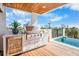 This outdoor kitchen on the deck features a built-in BBQ, bar fridge, and seating area with ocean views at 322 Beach Rd, Sarasota, FL 34242