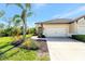 Home showcasing an attached two-car garage, well-maintained lawn, and a beautifully landscaped garden bed at 324 Casalino Dr, Nokomis, FL 34275