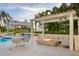 Beautiful poolside patio with a pergola overhead, providing shade for a relaxing dining and lounge area at 35 Watergate Dr # 1402, Sarasota, FL 34236