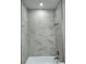 Bathroom featuring white marbled-look tiles, shower and tub, and updated fixtures at 3525 Mcintosh Rd, Sarasota, FL 34232