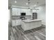 This spacious kitchen features white cabinets, stainless appliances, a center island, and wood-look flooring at 3525 Mcintosh Rd, Sarasota, FL 34232