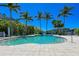Stunning community pool surrounded by lush tropical greenery and swaying palm trees at 384 Aruba Cir # 103, Bradenton, FL 34209