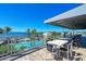 Outdoor patio with dining tables overlooking pool, palm trees, and ocean views, perfect for outdoor dining at 384 Aruba Cir # 103, Bradenton, FL 34209