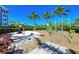 Community playground area featuring various playground equipment, mulch, and palm trees against a clear blue sky at 384 Aruba Cir # 103, Bradenton, FL 34209