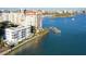 Breathtaking aerial view of condo with a pool and dock along the waterfront, next to tropical landscaping at 400 Golden Gate Pt # 51 & 52, Sarasota, FL 34236