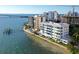 Amazing aerial view of waterfront condo with a pool, lush tropical landscaping, and dock along the coastline at 400 Golden Gate Pt # 51 & 52, Sarasota, FL 34236