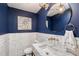 Stylish powder room featuring elegant fixtures, navy walls, and marble mosaic wall paneling at 400 Golden Gate Pt # 51 & 52, Sarasota, FL 34236