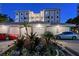 Elegant entrance with lush landscaping, decorative rocks, and palm trees in front of condo building at 400 Golden Gate Pt # 51 & 52, Sarasota, FL 34236