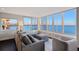 Bright living room featuring a comfortable gray sofa, large windows, and stunning water views at 400 Golden Gate Pt # 51 & 52, Sarasota, FL 34236