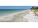 Scenic beach view with clear water, soft sand, and distant buildings against a blue sky at 455 Longboat Club Rd # 407, Longboat Key, FL 34228